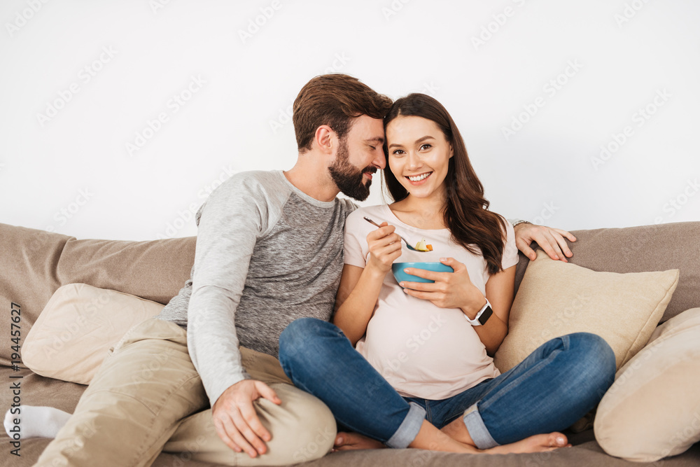 Lovely young pregnant couple relaxing on a couch together