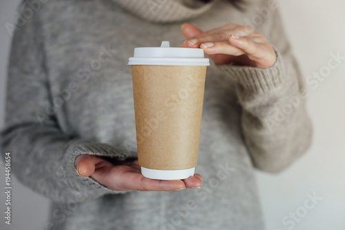 Blank take away kraft coffee cup on grey pullover background. Mock up for logo or design.