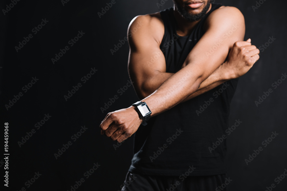 Naklejka premium cropped shot of muscular african american man stretching hands isolated on black