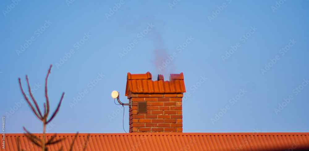 Fototapeta premium Red chimney with bricks, roof and sky background