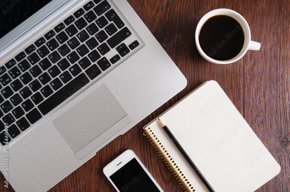 Notepad, laptop with pencil, smartphone, glasses and coffee cup on wood table. Flat lay. Notepad, laptop with pencil, smartphone, glasses and coffee cup on wood table. Flat lay.