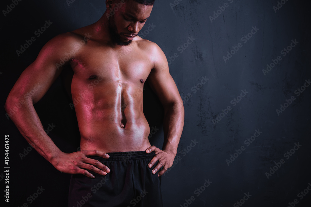 muscular bare-chested african american man standing with hands on waist and looking down on black