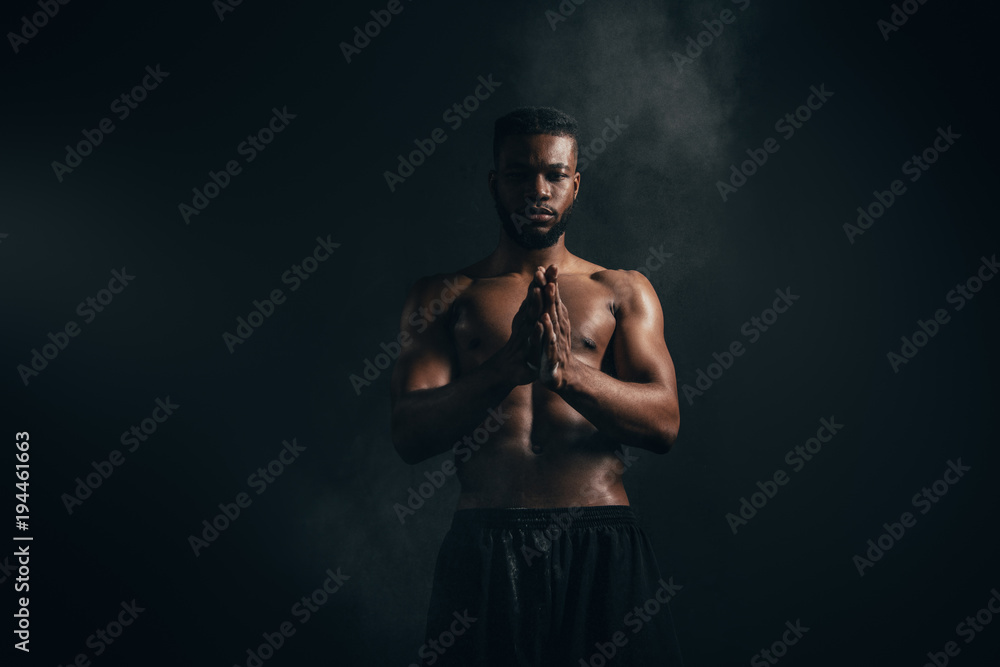 young african american sportsman applying talcum powder and looking at camera on black