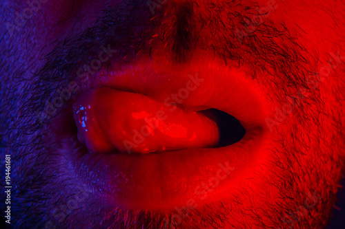 Macro close up on man with seductive facial expression sticking out his tongue licking his lips