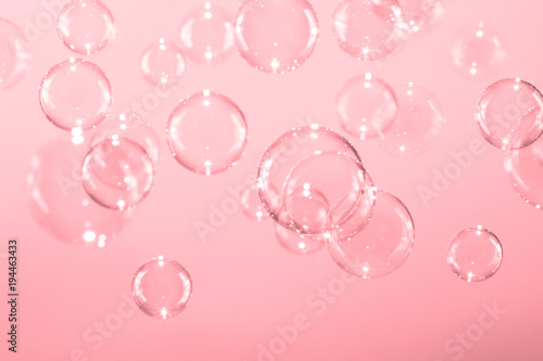 Beautiful bright soap bubbles floaing on pink background