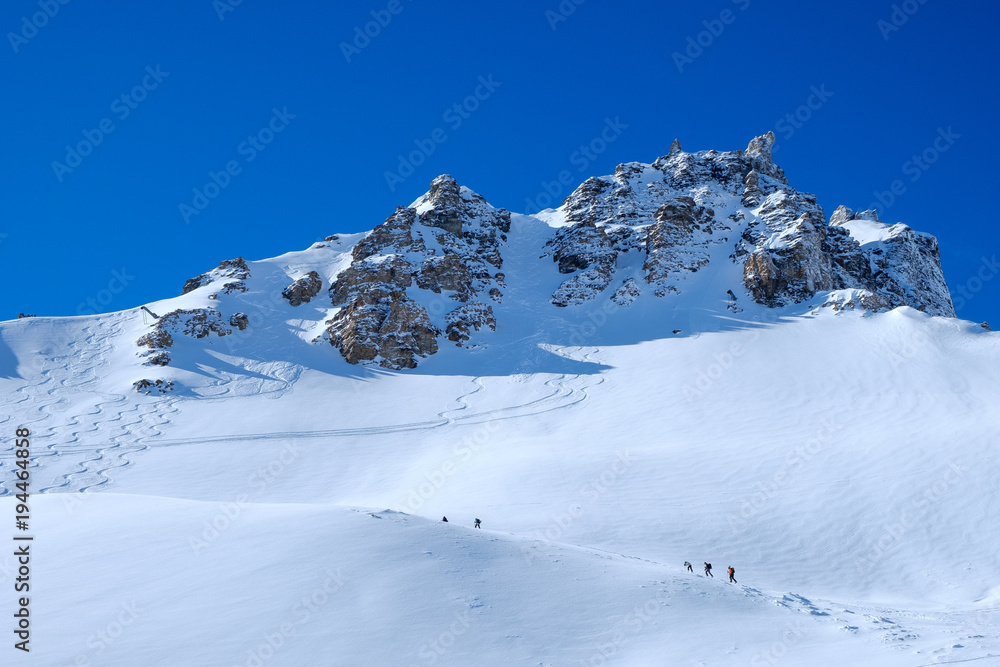 Paraglider starts in winter mountain landscape, shot against the sun, blue sky, horizontal