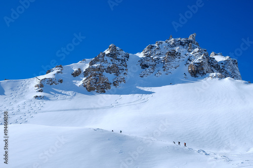 Paraglider starts in winter mountain landscape, shot against the sun, blue sky, horizontal