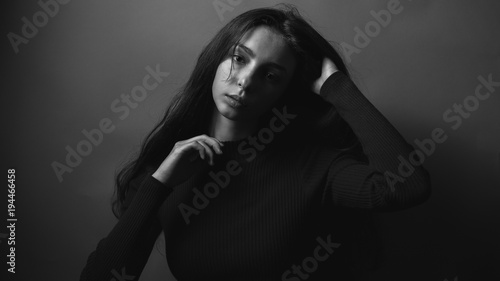 Gentle young female with long hair in studio. Black and white
