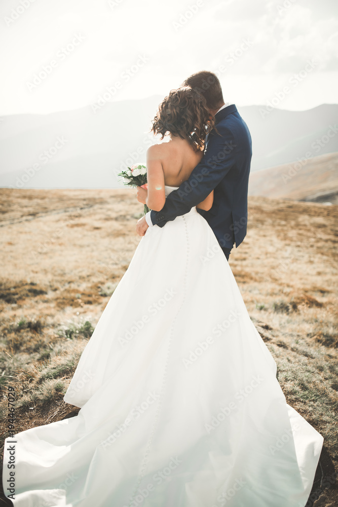 Obraz premium Happy beautiful wedding couple bride and groom at wedding day outdoors on the mountains rock. Happy marriage couple outdoors on nature, soft sunny lights