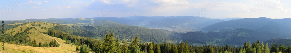 Panorama in beautiful mountains covered with forests and meadows trail to the horizon