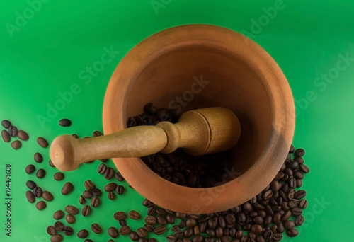 a clay pot, grind the coffee beans. green background