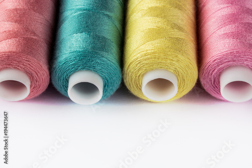 Sewing supplies and accessories for needlework. coils of yellow pink green thread for sewing clothes on white background.