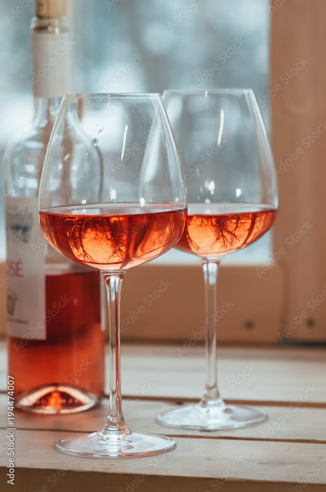 A closeup of rose wine bottle and two filled glasses