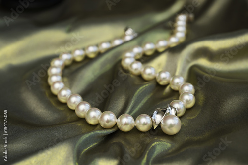 Pearl necklace on a Golden green fabric.