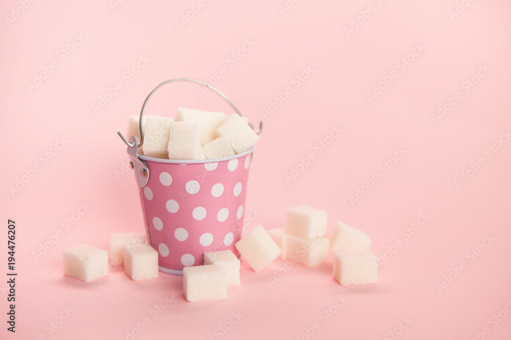 Sugar cubes in little bucket on pink background, sweet food Sugar cubes in little bucket on pink background, sweet food