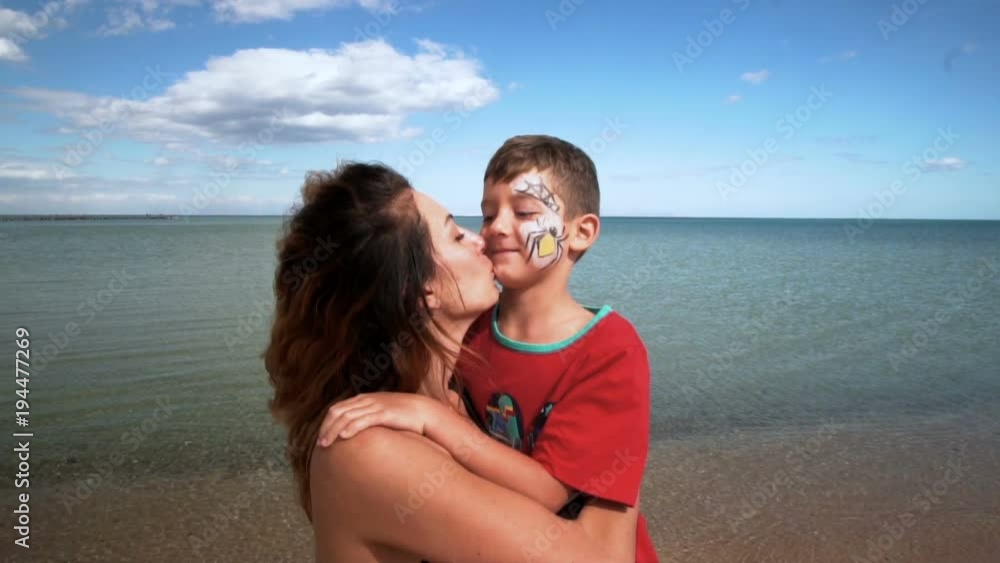 Child and mom on a beach are played, embrace and kiss. Slow motion. 120 fps Child and mom on a beach are played, embrace and kiss. Slow motion. 120 fps