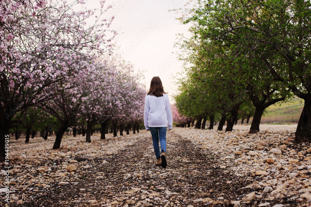 teen girl walking on rural blossom park. back shot teen girl walking on rural blossom park. back shot