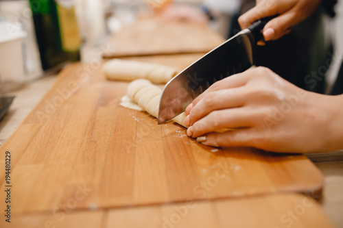 Girl cuts the dough for making Italian pasta