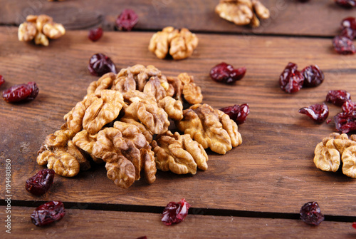 Walnut and dry cranberries on a dark wooden background.