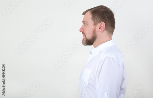 Side view male. Portrait in the profile of bearded man in white shirt looking on copy space.