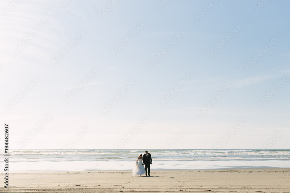 Bride and Groom Walking towards the Ocean Bride and Groom Walking towards the Ocean