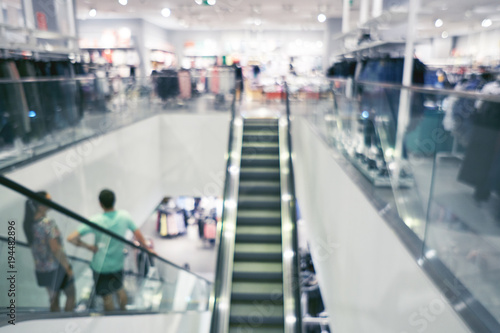 Blurred background of a modern shopping mall. Big sales on Black Friday for Christmas. Escalators. Blurred showcases fashion boutique with clothes. People make shopping © Max Larin