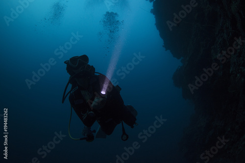 Scuba diver diving in the night with torch light photo