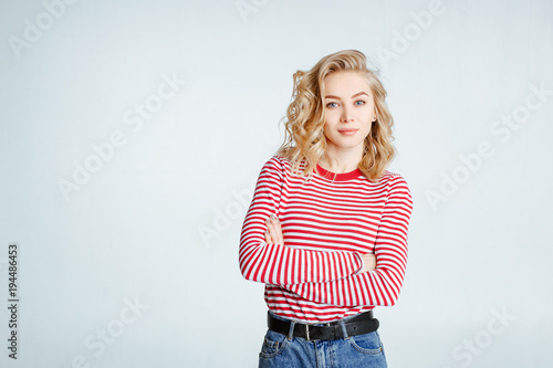 The lovely girl the blonde in stylish glasses poses on a white background. Emotions. Body language. The woman looking at camera with serious or pensive expression