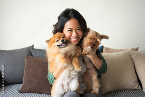 Happy Woman Holding Yorkie and Spitz Dogs on Sofa