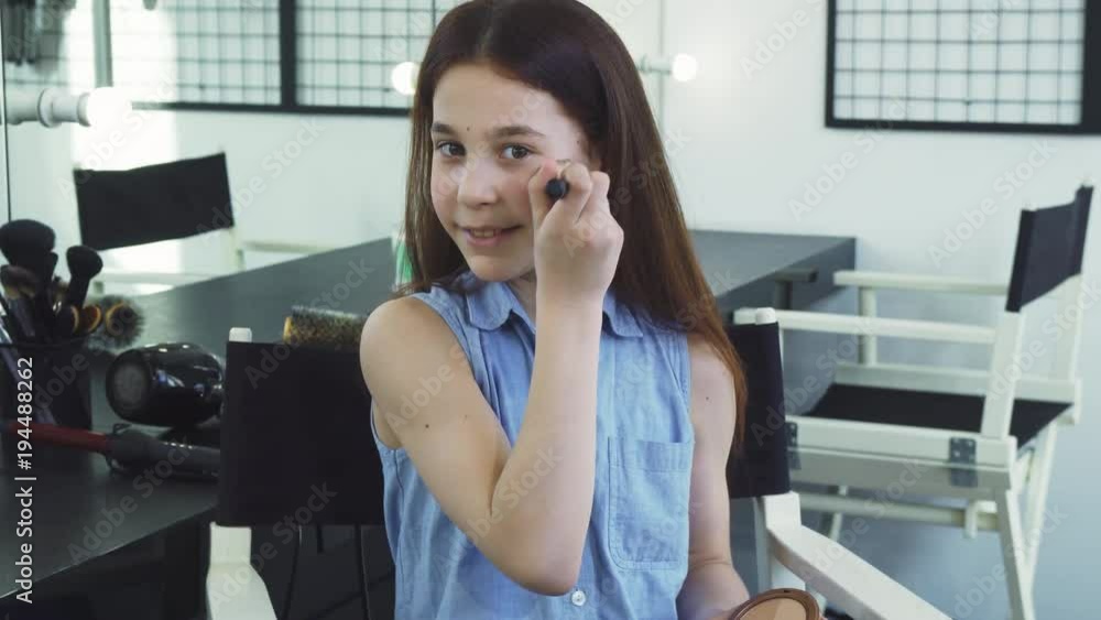 Cute cheerful little girl smiling applying makeup having fun pretending to be an adult beauty fashion cosmetics face skin flawless artist visage femininity posing playful growing up actress. Cute cheerful little girl smiling applying makeup having fun pretending to be an adult beauty fashion cosmetics face skin flawless artist visage femininity posing playful growing up actress.