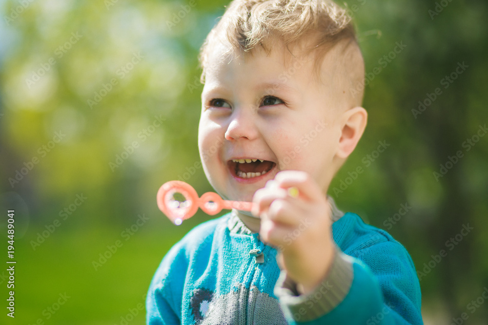 The boy blows out soap bubbles and laughs out loud. Happy child outdoors. The boy blows out soap bubbles and laughs out loud. Happy child outdoors.