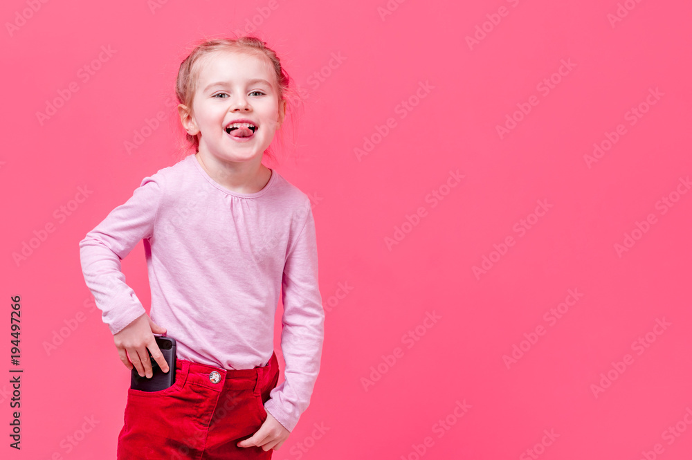 Little girl shows tongue and puts her cellphone in pocket Little girl shows tongue and puts her cellphone in pocket