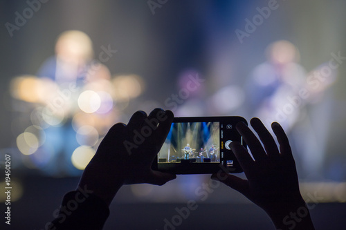 Fan holding smartphone and recording or taking picture during a  concert