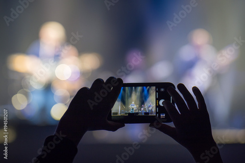 Fan holding smartphone and recording or taking picture during a concert