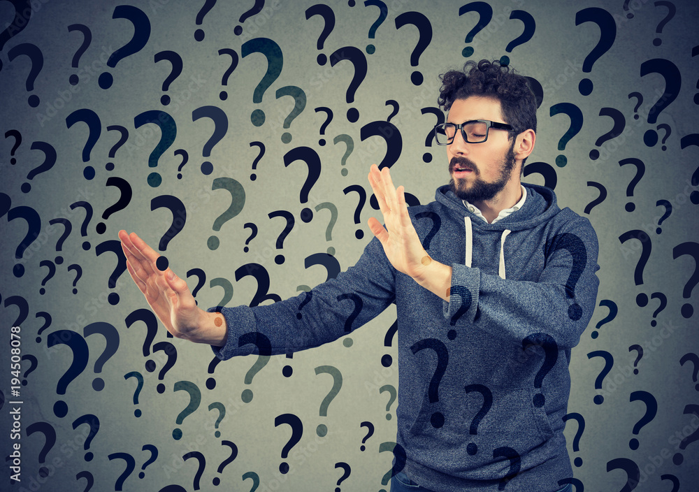 Young hipster man with eyes closed looking for answer among plenty of questions. Young hipster man with eyes closed looking for answer among plenty of questions.