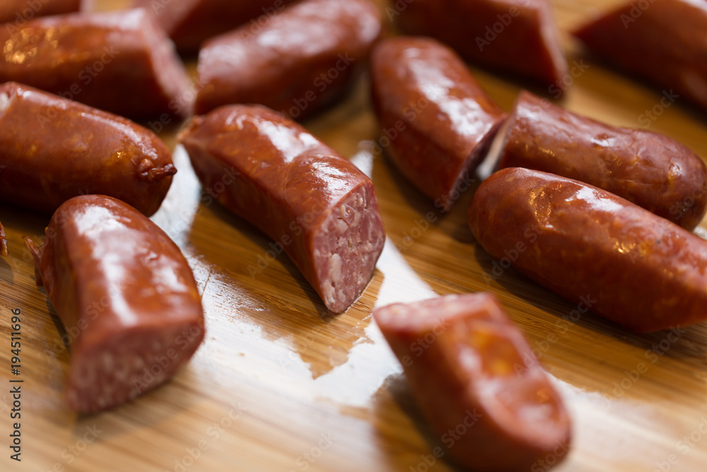 Spicy sausage chorizo cut in pieces on a hard wood cutting board - close up Spicy sausage chorizo cut in pieces on a hard wood cutting board - close up
