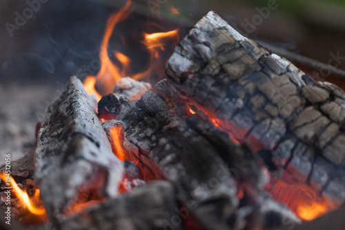 Fire with charcoals. Burning wood. Macro. Live flames with smoke. Wood with flame for barbecue and cooking bbq. Bright color. Orange