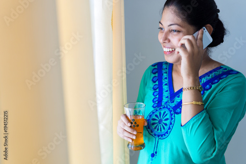 Happy woman drinking juice and talking on mobile phone photo