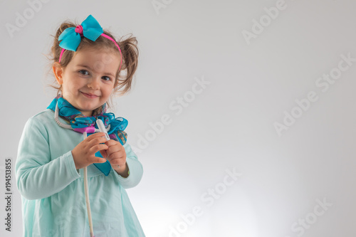 Cute kid girl playing doctor with toy at home