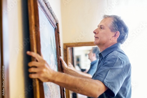 Man hanging artwork on a wall photo