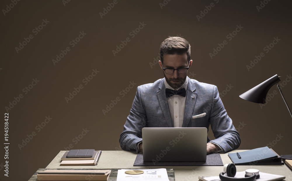 Businessman working on laptop at office desk Businessman working on laptop at office desk