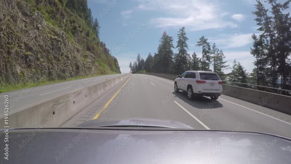 Car cruises by lush mountain side along the Sea to Sky Highway in Canada Car cruises by lush mountain side along the Sea to Sky Highway in Canada