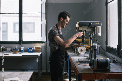 Artisan glasses maker is working with machinery in his atelier photo
