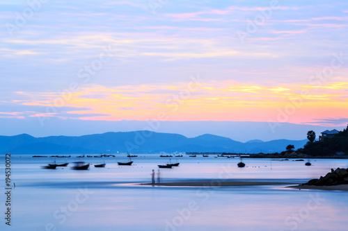 Beach in Rayong Thailand taken Photo with slow shutter speed to create 'smokey' style waves, Colorful sky during sunset, plenty of fishing boat, Motion blur