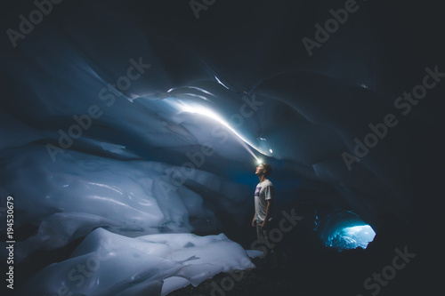 Young man looking toward the ceiling of an ice cave with his headlamp