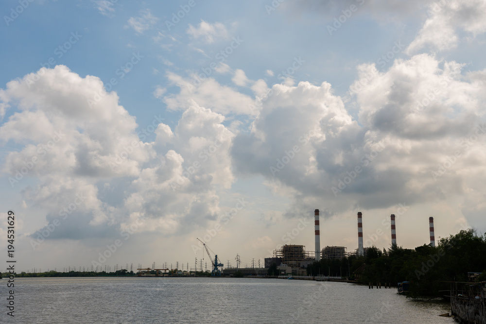 Power plant cooling tower and crane situated near the river with cloudy sky background Power plant cooling tower and crane situated near the river with cloudy sky background