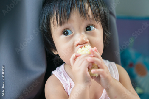Asian baby eating corn and holding it by himself in day time