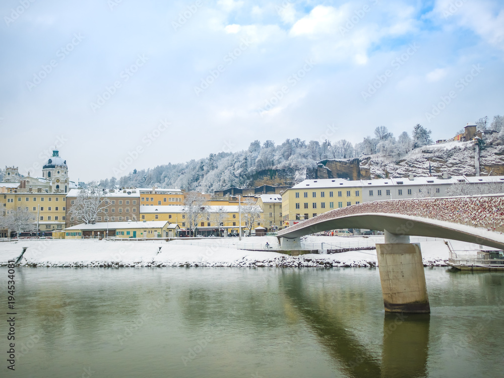 landscape view of the famous historic city of Salzburg with Salzach river in beautiful bridge  sky and clouds winter season snow Austria