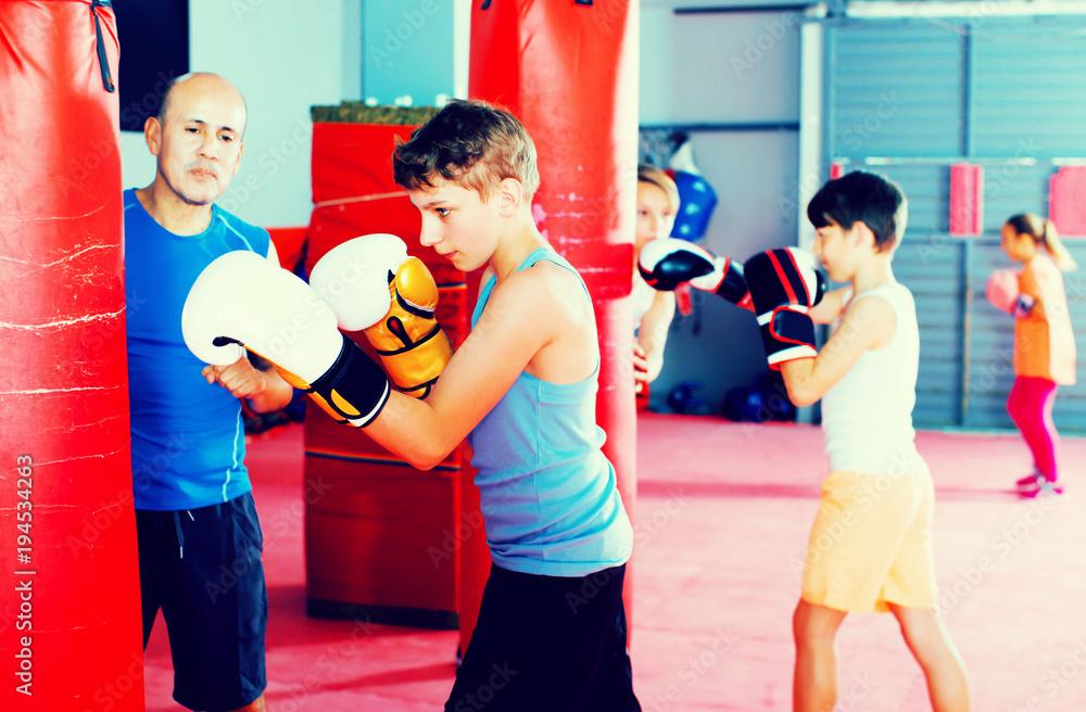 Boxing instructor and young children practicing blows