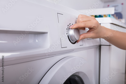 Woman Turning Button Of Washing Machine